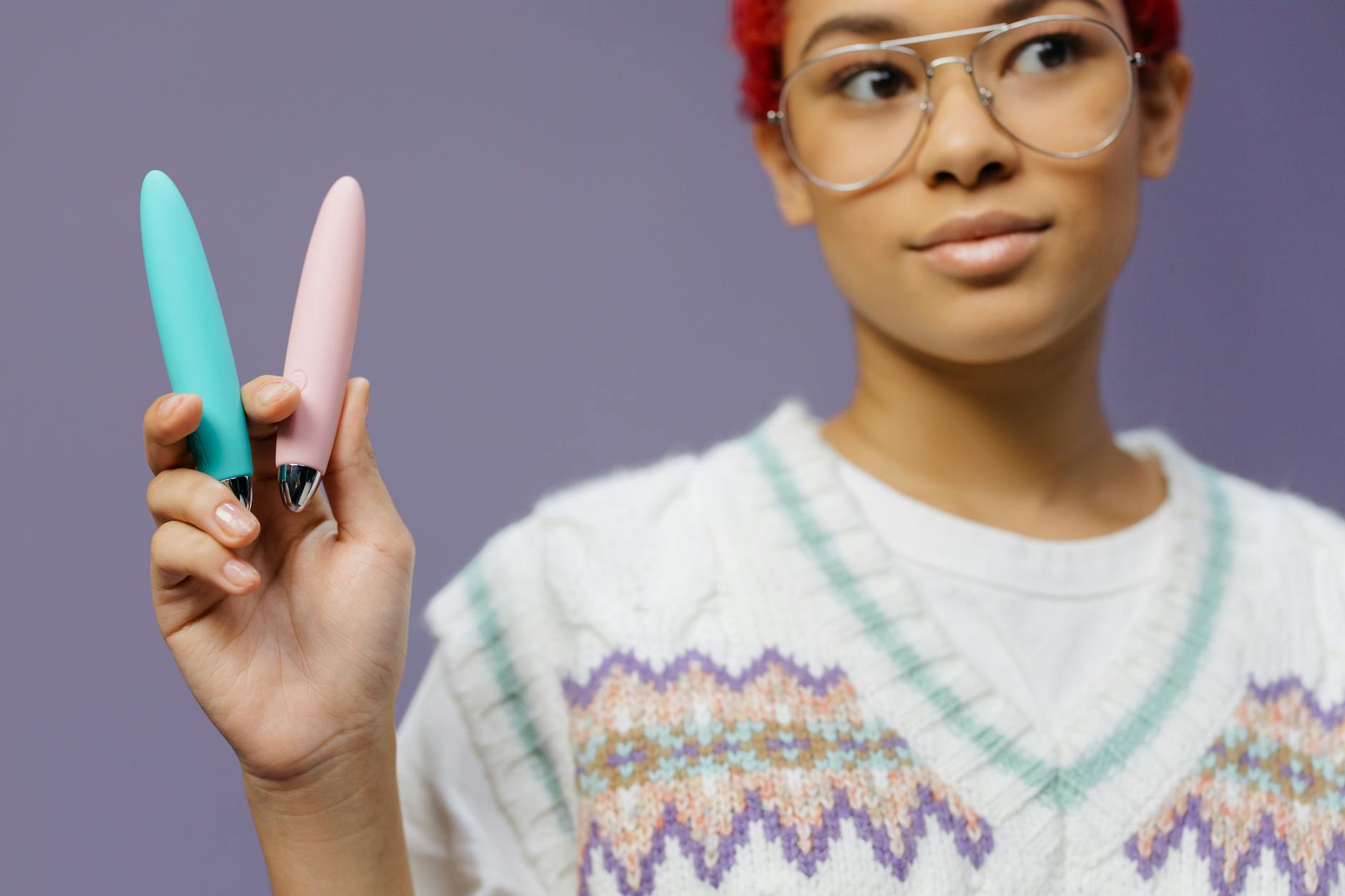 Two hands holding colorful vibrators together, representing couple intimacy and connection