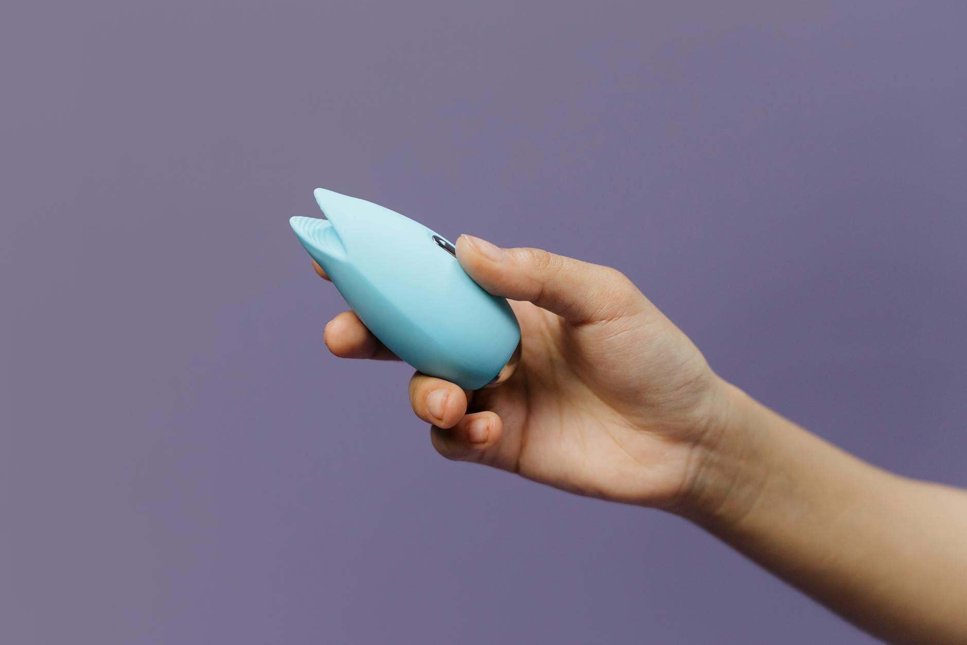 A lemon vibrator held in hand against a purple background, ready for mindful pleasure exploration