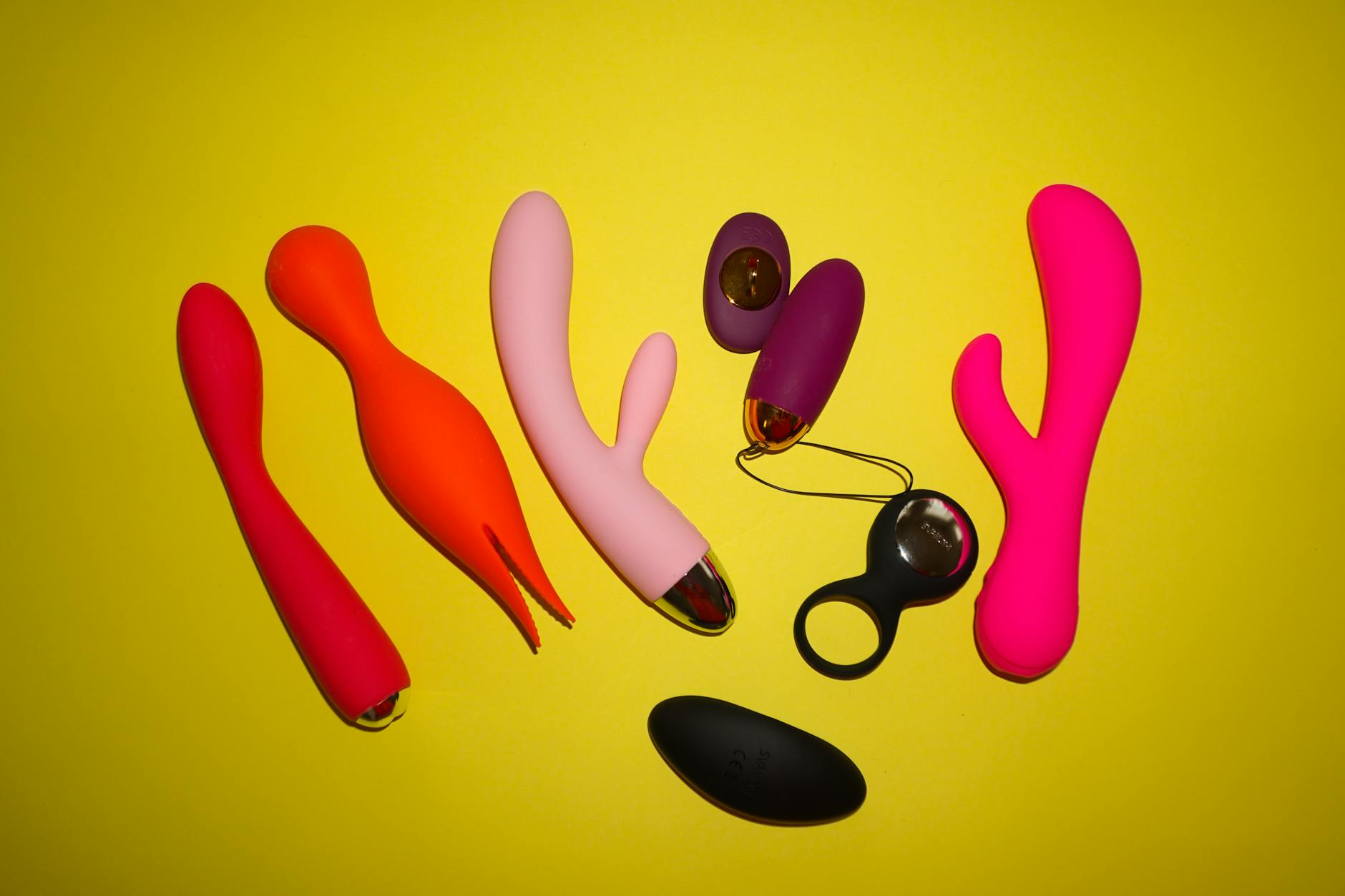 Colorful sex toys displayed on a bright yellow background, representing diverse approaches to solo pleasure and reconnection